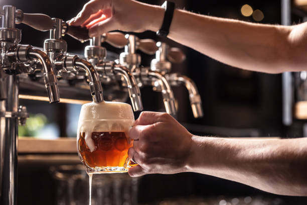 istock Hands of the pub employee tapping beer into a rounded mug. 1381344692