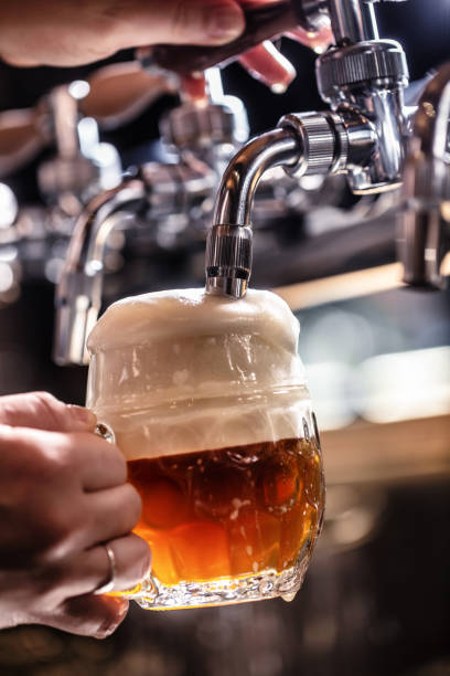 istock Mixing dark beer with light in one mug by tapping it from a tap, creating rich foam. 1381344701