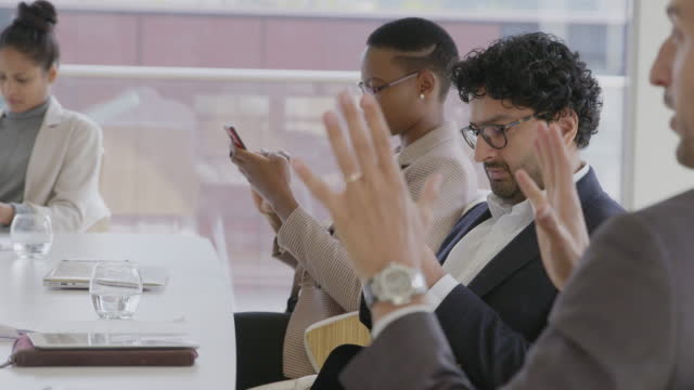 Business people using smart phones in conference room meeting
