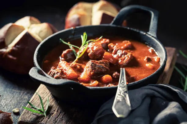 Hot and tasty goulash served with fresh hot buns on dark plate