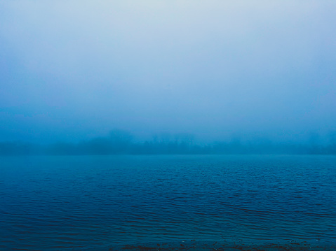 A creepy lake in the fog in cold weather in winter.