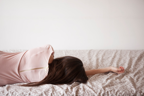 rear view of a woman lying in bed in the morning light.