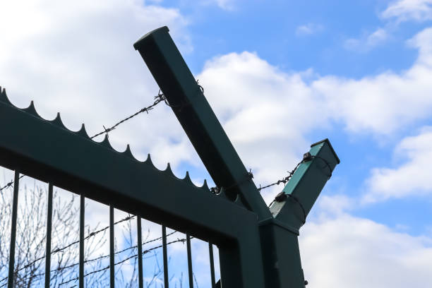 istock Barbed wire against a cloudy sky on a big fence at a border. 1381407104