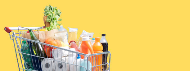 Full shopping cart on yellow background stock photo