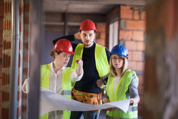istock team of engineers in vests and hard hats with schematics on a construction site 1381421841
