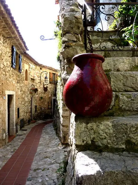 Photo of Street of Eze old village, south France, with a red pottery on the stairs