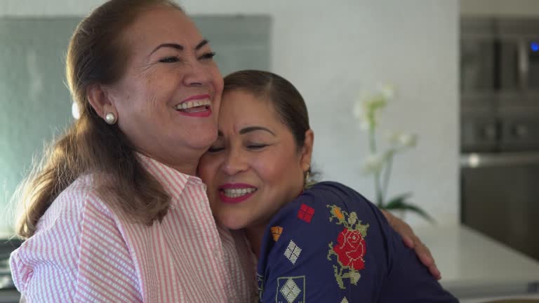 Female Latin friends embracing and laughing at home