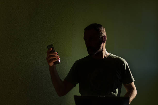 silueta del hombre mirando el teléfono móvil - shadow focus on shadow people men fotografías e imágenes de stock