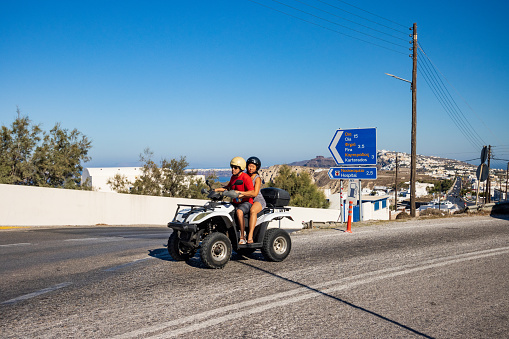 Two Tourists having fun on a Quadbike on Santorini in South Aegean Islands, Greece
