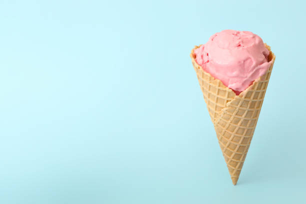 istock Delicious pink ice cream in waffle cone on light blue background. Space for text 1381473199