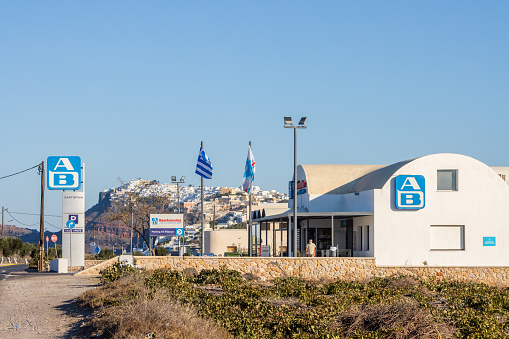 AB Supermarket near Firá on Santorini in South Aegean Islands, Greece, with people and car number plates visible
