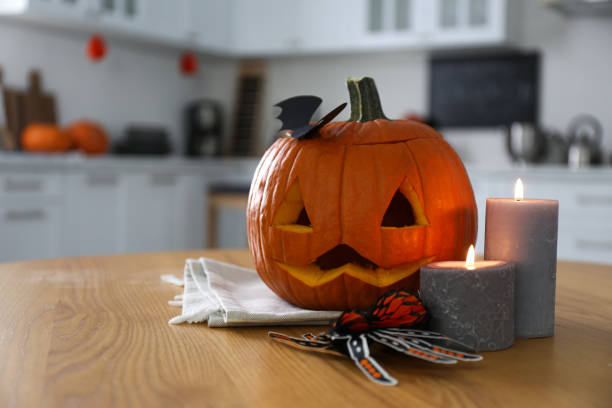 istock Pumpkin jack o'lantern, candles and Halloween decor on wooden table in kitchen, space for text 1381497121