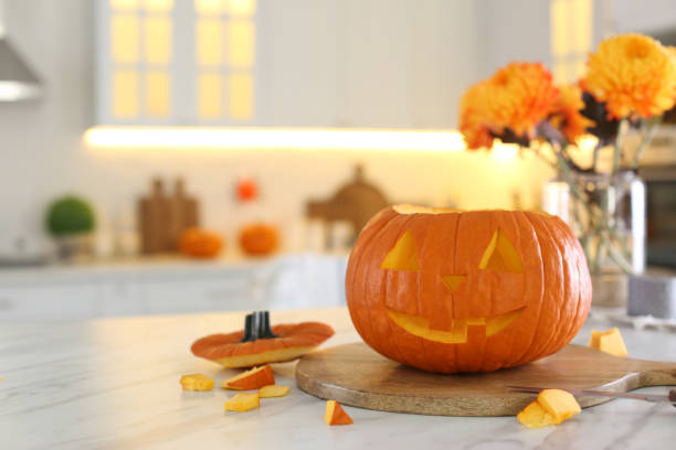 istock Pumpkin jack o'lantern on white marble table in kitchen, space for text. Halloween celebration 1381508613