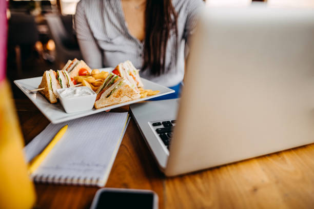Photo of a young woman working on her laptop while having breakfast in cafe