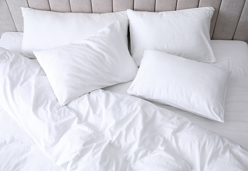 Comfortable bed with soft white pillows, closeup