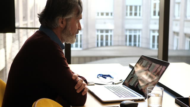 Mature businessman in office, having video call with remote colleague
