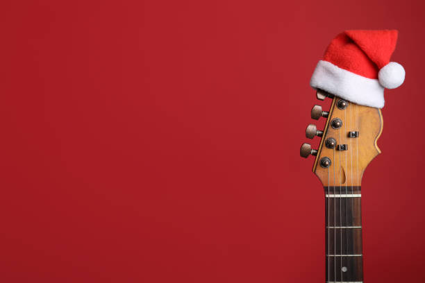 istock Guitar with Santa hat on red background, space for text. Christmas music concept 1381531670