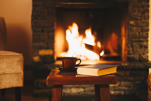 Cup of hot drink in front of warm fireplace. High quality photo