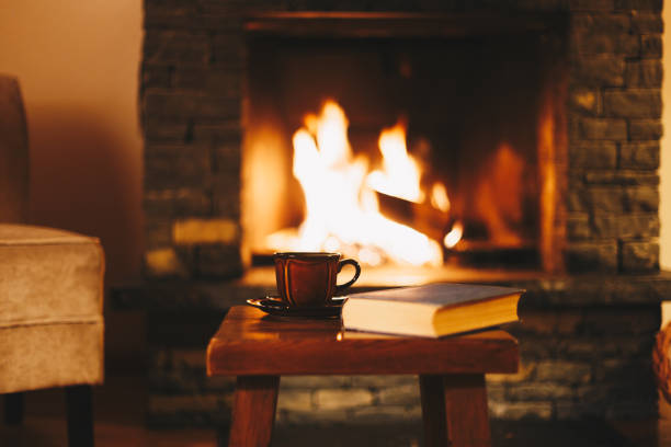 cup of hot drink in front of warm fireplace - şömine stok fotoğraflar ve resimler