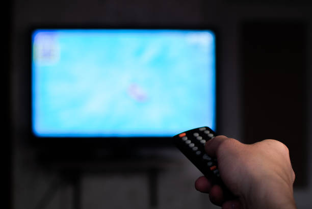 istock Hand switch channels by remote control. Unfocused TV, close up hand 1381551989