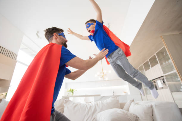 istock Father holding son in superhero costume 1381572024
