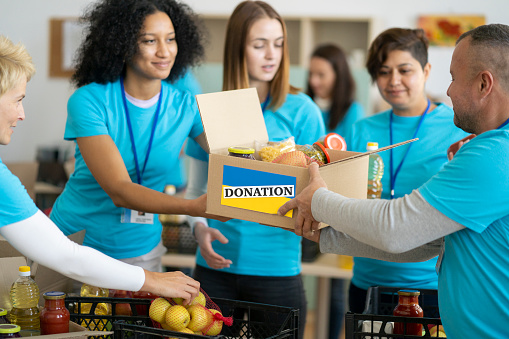 Charity workers placing food into donation boxes for a community outreach food drive of support and help people in Ukraine