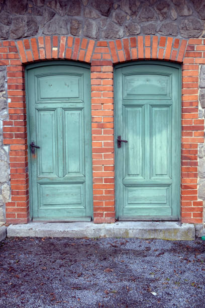 istock two old green wooden doors at building with brick wall 1381596083