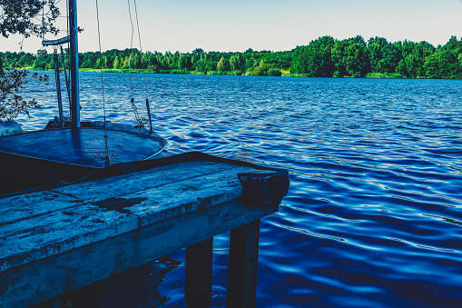 A dock with a sailing ship on a lake.
