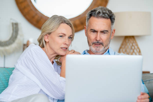 istock Mature couple using laptop computer sitting on the sofa. 1381611665