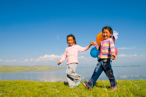 Two Asian girls playing in a meadow.