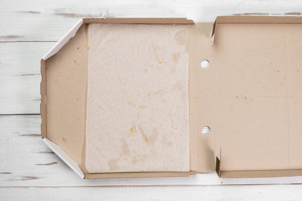 istock Empty open pizza box. White wooden background. Eaten pizza. Top view. 1381643800