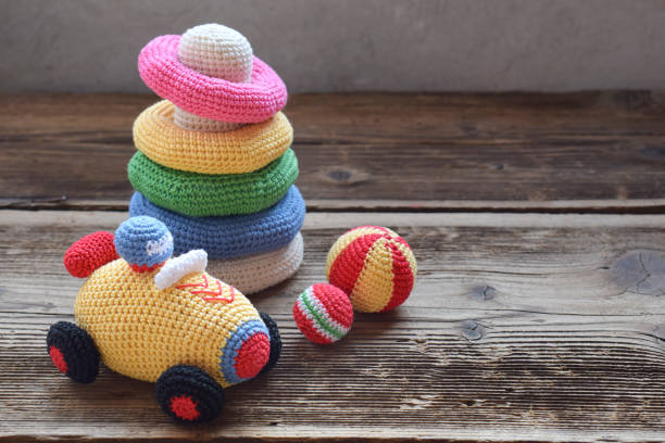 farbige häkeln rennwagen und pyramide aus farbigen ringen. spielzeug für babys und kleinkinder, um mechanische fähigkeiten und farben zu lernen. handgefertigte handwerk. diy-konzept. - cotton ball blue cotton crochet stock-fotos und bilder