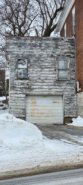 An old dilapidated garage with peeling wood siding and a white rusty door in yarker ontario canada