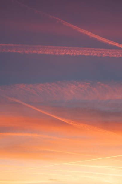 wunderschöner abenddämmerungshimmel in mehreren farben, der durch flugzeugwege verbessert wird. - vapor trail sky night sunset stock-fotos und bilder