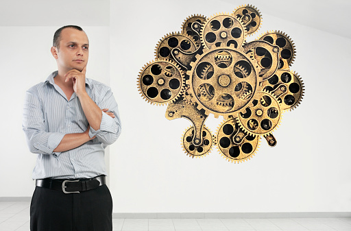 Man looking at an image of cogwheelss on a transparent board