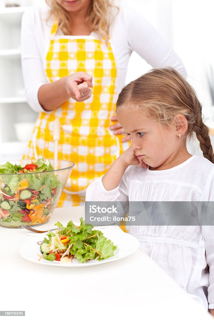 Training for a healthy eating habit Mother training a healthy eating habit in her child - eating vegetable salad Adult Stock Photo