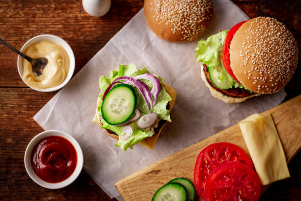 istock Cooking a hamburger. Stacking vegetables in a hamberger. The ingredients are different on a wooden background. Hamburger day. 1381705190