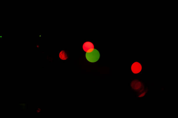 Defocused Christmas background with bokeh effect specially shot with very dark background at night inside a home to allow for composit work.  The shot is of Christmas Tree lights indoors after dark. No People. Horizontal format.