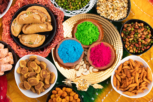 Holi Theme - Colorful Gulal, Abeer Or Abir With Shahi Mithai Gujia Or Gujiya, Crispy Snacks Namkeen Also Called Nimki, Mathri, Matar, Kachori, Namkin, Chidwa, Mixture, Bhujia, Bhakharwadi Or Bakarwadi