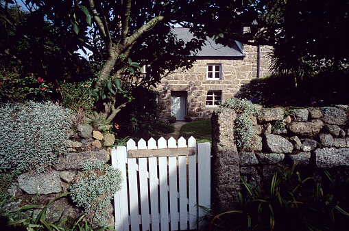 Early morning light cast shadows and silhouettes across a an idyllic country cottage in a Cornish village