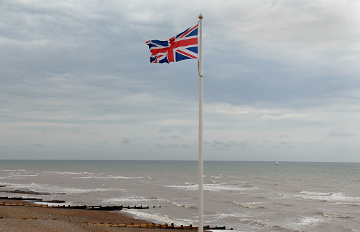 A British Union Jack national flag flies beside the English Channel on the South coast of England