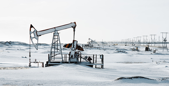 Oil frozen pump and snowy cold winter, cloudy gray sky