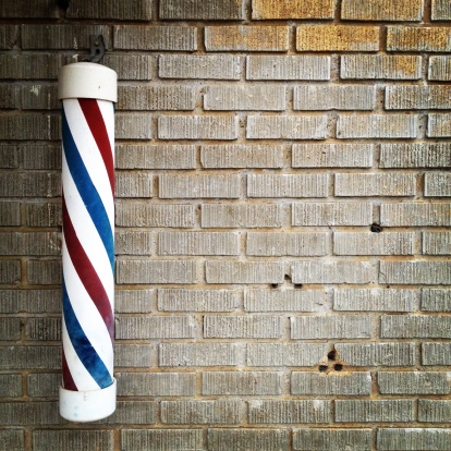Barber shop pole on gray brick wall