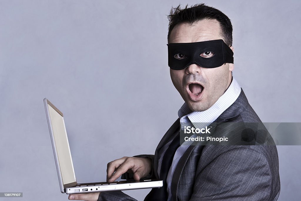 Businessman with mask and  laptop Businessman with mask and laptop. Computer Hacker Stock Photo