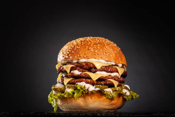 quadruple burger with cheese cucumber and lettuce. isolated on black background.. - hamburger burger symmetry cheeseburger imagens e fotografias de stock