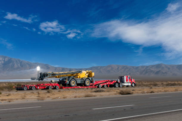 sattelschlepper, der einen großen dirt mover auf einer vierspurigen autobahn in der nähe der ivanpah solar power facility transportiert - four lane highway stock-fotos und bilder