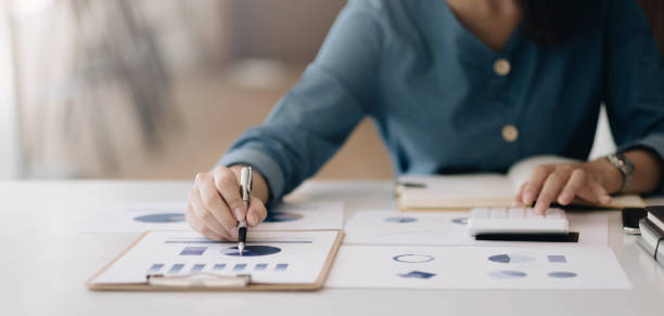 istock cloas up woman pointing at papwework and using calculator. 1381898020