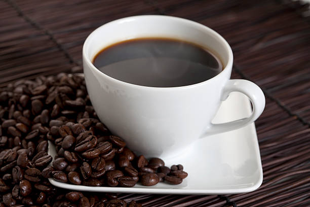 Hot Cup z czarnej kawy z fasoli na talerzu – zdjęcie