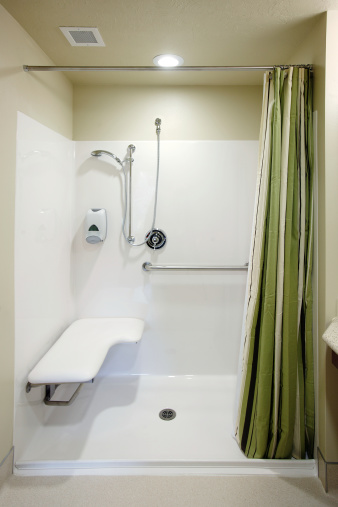 An image of the safety bars, seat and plumbing fixtures in a roll in shower stall