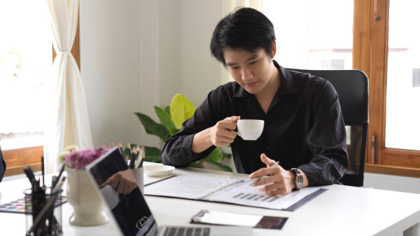 istock Businessman sipping coffee while looking at the financial data 1381918499